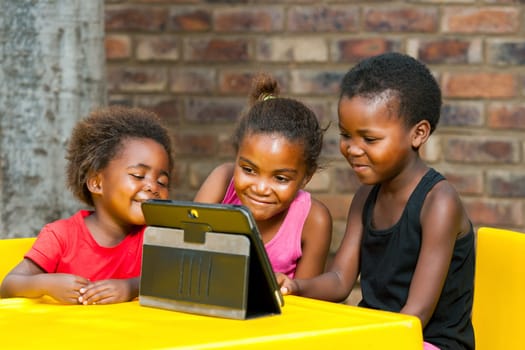 Close up portrait of three african young girls playing together on digital tablet.