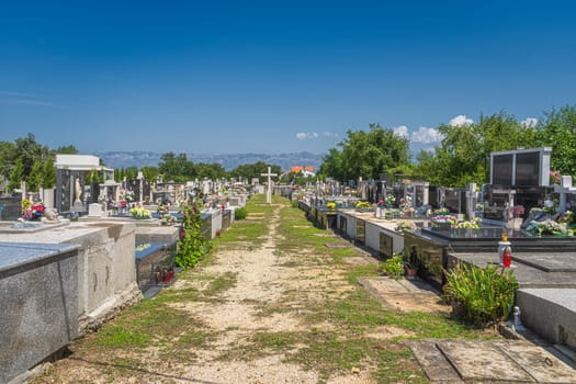 Graveyard next to Church of the Nativity of the Blessed Virgin Mary in Zaton with Dinaric Alps in a background, Croatia
