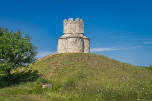 Small tower like 11th century St. Nicholas church located on small hill with green tree beside, between Nin and Zaton in Croatia