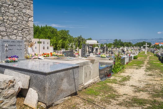 Graveyard next to Church of the Nativity of the Blessed Virgin Mary in Zaton with Dinaric Alps in a background, Croatia