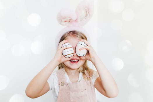 Little girl with Easter eggs and bunny ears hat. High quality photo