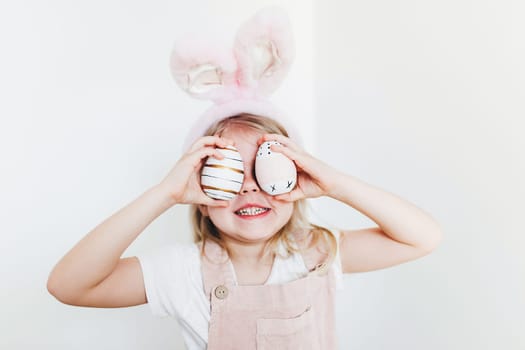 Little girl with Easter eggs and bunny ears hat. High quality photo