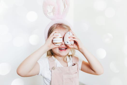Little girl with Easter eggs and bunny ears hat. High quality photo