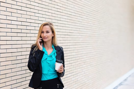 Successful businesswoman or entrepreneur talking on cellphone while outdoor. City business woman working.