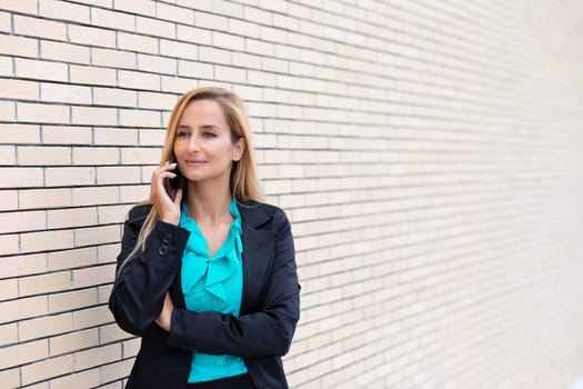 Successful businesswoman or entrepreneur talking on cellphone while outdoor. City business woman working.