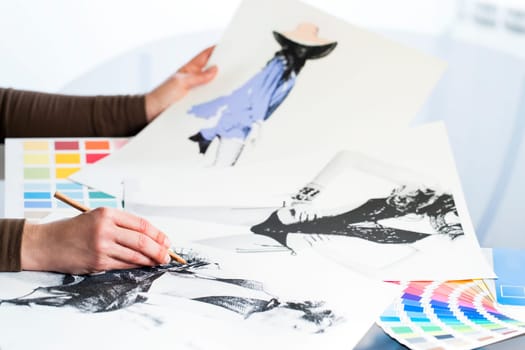 Extreme close up of fashion designer at work with fashion sketches and color charts.
