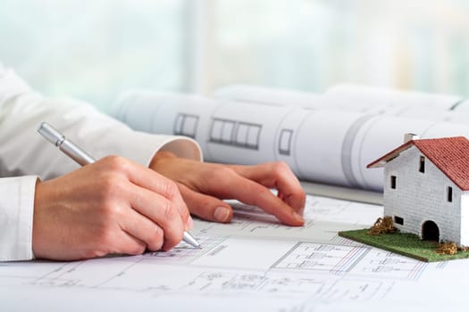 Close up of female hands working on architectural blueprints.