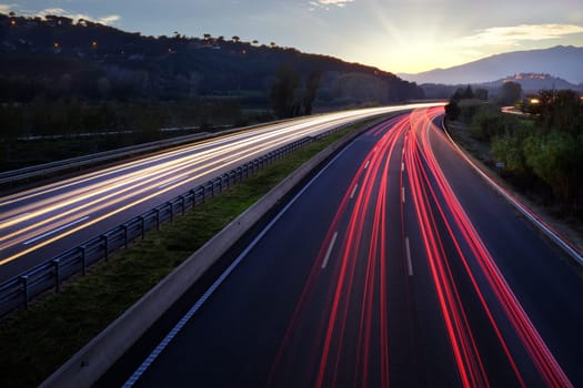 Colorful Light beams of moving vehicles on busy highway at dusk.