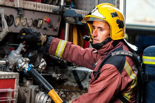 Fireman controlling water pressure at back of fire truck.