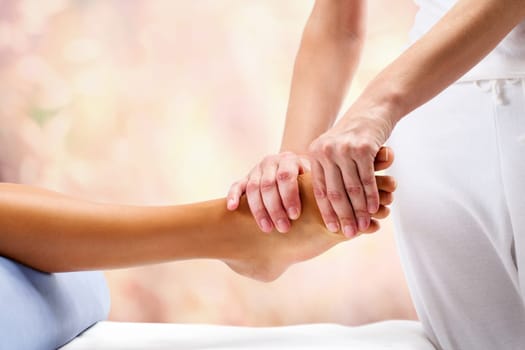 Osteopath doing reflexology massage on female foot against colorful background.