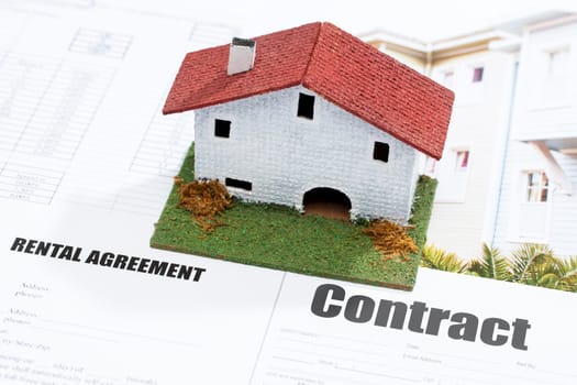 Macro close up of conceptual small toy house on contract documents.