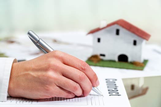 Close up of female hand filling out real estate buying and selling contract.