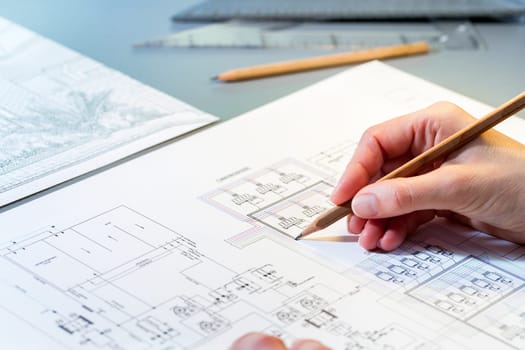 Macro close up of quantity surveyors hand reviewing technical drawing.