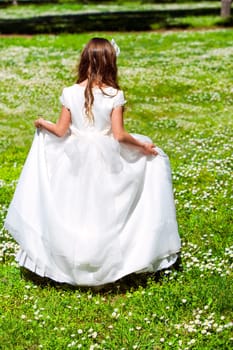 Young girl in white dress walking in flower field.