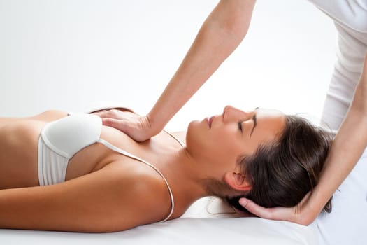 Close up of osteopath doing thorax manipulation massage on young woman.One hand doing physical force on chest and on hand behind head.