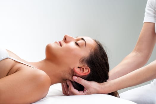 Close up of  chiropractor pressing back of womans head. Therapist doing healing massage with fingers at back of neck.