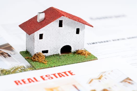 Close up of small toy house on real estate documents.