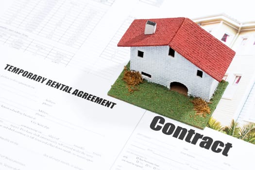Close up of small toy house on real estate documents.