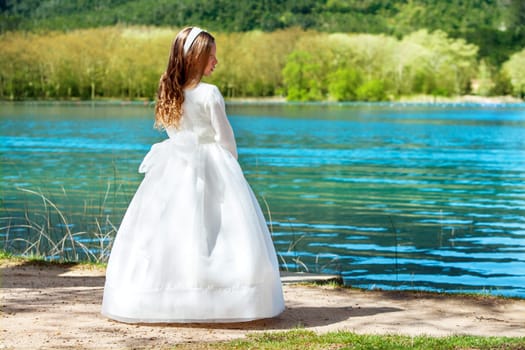 Full length portrait of cute girl in white dress at lake.