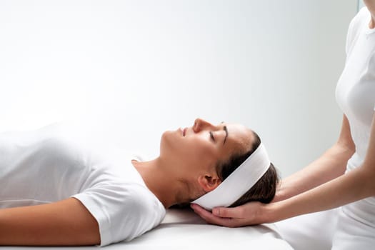 Close up portrait of young Woman relaxing with eyes closed at reiki session.Girls head resting on therapist hands.