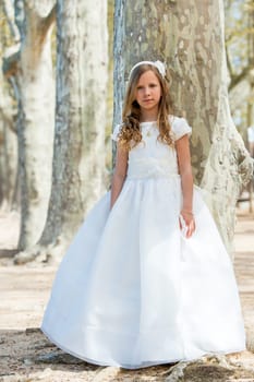 Full length portrait of cute girl in white dress in forest.