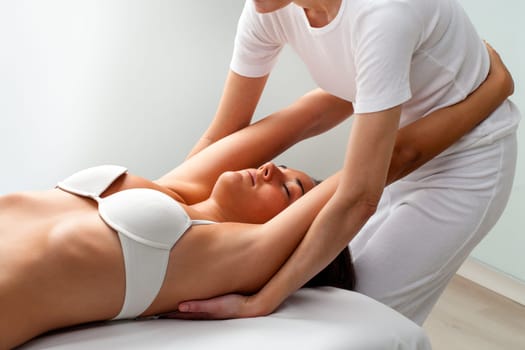 Young woman receiving osteopathic treatment. Osteopath stretching girls arms.