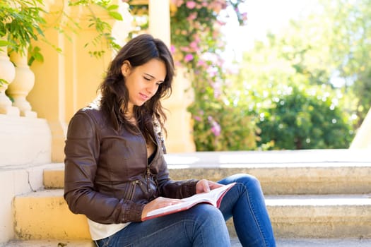 Young woman reading a book and relaxing at the park