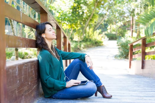 Young woman listening to music at the park