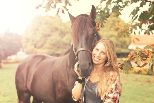 Beautiful and natural young woman spending sometime with her horse