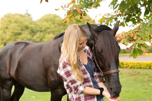 Beautiful and natural young woman spending sometime with her horse