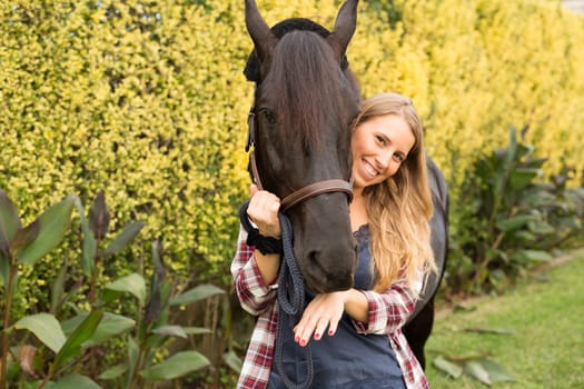 Beautiful and natural young woman spending sometime with her horse