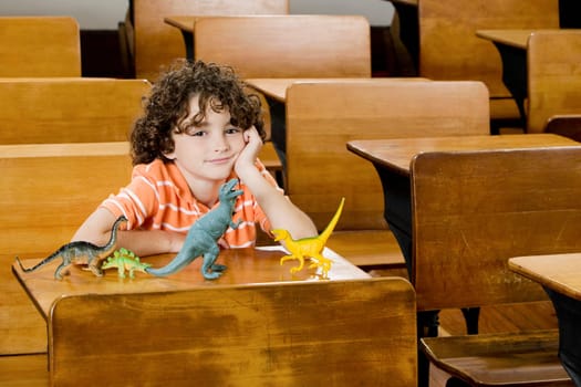 Schoolboy sitting with toys in a classroom