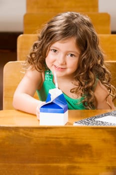 Schoolgirl sitting with a juice packet in a classroom