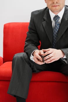 Businessman holding a mobile phone and sitting on the couch