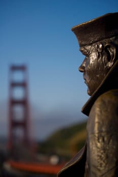 Close_up of a statue with a bridge in the background, The Lone Sailor, Golden Gate Bridge, San Francisco Bay, San Francisco, California, USA