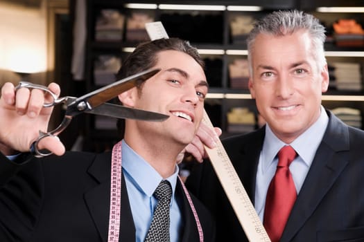 Tailor holding a scissors with a businessman in a clothing store