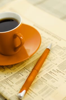 Close_up of a pen and tea cup on a financial newspaper