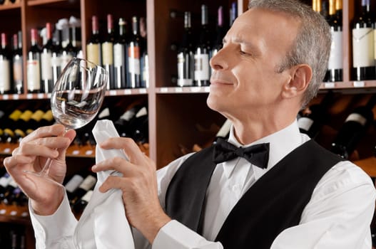 Waiter cleaning a wine glass in a bar
