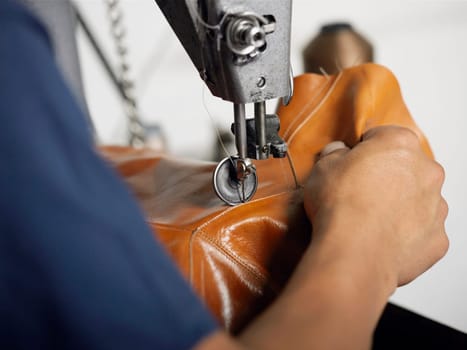 Close_up of a personŽs hand using a sewing machine in a shoe factory