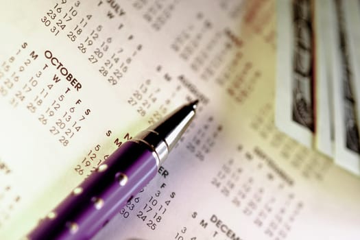 Close_up of a pen and paper currency on a calendar