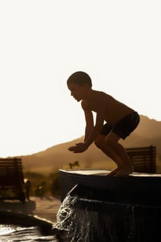Boy preparing to jump into a swimming pool