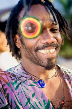 Portrait of a young man smiling with a necklace over his eye