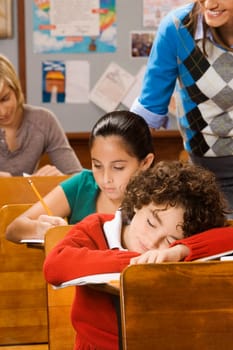 Students studying with a schoolboy sleeping in a classroom