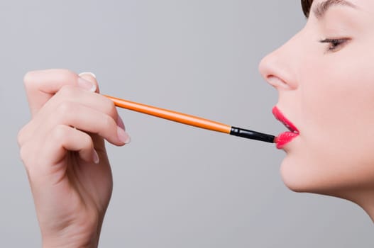 Close_up of a young woman applying lipstick