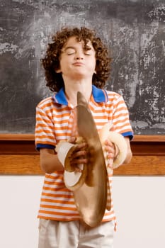 Schoolboy playing cymbals in a classroom