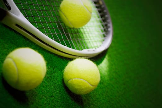 Close_up of three tennis balls with a tennis racket in a court