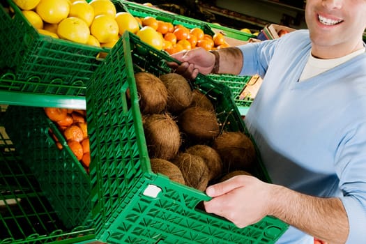 Man carrying a crate of coconuts in a supermarket