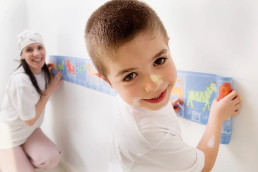 Portrait of a boy and his mother pasting wallpaper
