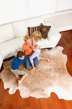 Woman playing with her son and a daughter in a living room