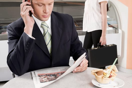 Businessman talking on a mobile phone in an ice cream parlor